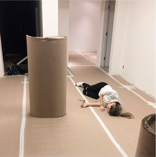 Liana deitada no chão forrado da obra de uma das lojas